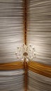 Vertical low angle shot of a chandelier in the ceiling with white and yellow textiles Royalty Free Stock Photo