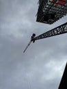 Vertical low angle shot of a construction crane during building process against the cloudy sky Royalty Free Stock Photo