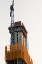 Vertical low angle shot of a crane near a building in the process of construction Royalty Free Stock Photo