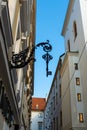 Vertical low angle shot of a ornamental black iron key hanging from white building wall