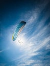Vertical low angle shot of a paraglider under the sunlight and a blue sky at daytime