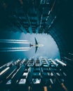Vertical low angle shot of a plane flying over a modern downtown building leaving a trail Royalty Free Stock Photo