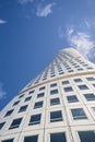 Vertical low angle shot of a tall twisting building on a blue sky background