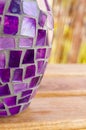 Vertical macro shot of an old purple mosaic vase on a wooden surface