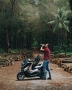 Vertical of a male model drinking water near a scooter in an Indonesian forest in Java Royalty Free Stock Photo