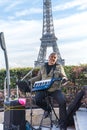 Vertical of a male musician with his instrument with the Eiffel Tower in the background.