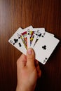 Vertical of a man holding clubs poker cards with assorted black color on a wooden background