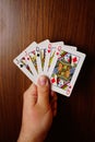 Vertical of a man holding poker cards with assorted combinations of queens and jacks
