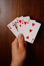 Vertical of a man holding red hearts poker cards against a wooden background