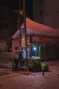 Vertical of a man selling grilled corn in a street in Bursa, Turkey captured at night