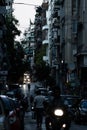 Vertical of a man walking down a dark street with motorcycle in the foreground in Athens, Greece.