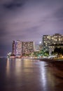 Vertical of modern buildings at night in Honolulu, Hawaii shot in long exposure near the sea