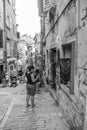 Vertical and monochrome shot of the people walking in a narrow street in center of Rovinj, Croatia