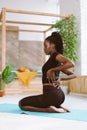 Vertical multiracial woman with dreadlocks stretching, do yoga exercises, sit on bending legs. Backache after training