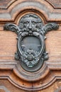 Vertical of an old metal door knocker with decorations and a lion's head on a rustic wooden door. Royalty Free Stock Photo