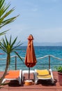 Vertical of an orange beach umbrella and lounge chairs in a  relaxing environment by the sea Royalty Free Stock Photo