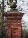 Vertical of ornate brick pillar of a gate against bare trees