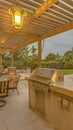 Vertical Outdoor kitchen and dining area under a pergola at the spacious patio of a home