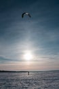 Alone ski kiter riding on a frozen snowy lake at winter cold sunset