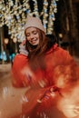 Vertical outdoor portrait of beautiful young woman in warm winter hat and jacket talking using mobile phone standing on Royalty Free Stock Photo