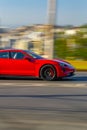 Vertical panning shot of Red Porsche Taycan speeding in the city street