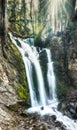 Vertical panorama of a gorgeous waterfall in lush green woods