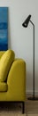 Simple black lamp next to yellow couch, vertical panorama