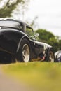 Vertical partial view of a black AC cobra parked on the grass