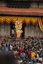 Vertical of people gathered around a decorated elephant outside temple at Thrissur Pooram festival