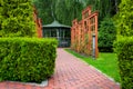 Vertical pergola made of brown wood in a roses garden with a stone tile walkway. Royalty Free Stock Photo