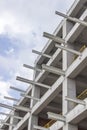 Vertical perspective shot of construction of a new reinforced concrete and metal beams linked building with open blue sky