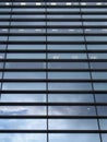 Vertical perspective view of the facade of a modern glass commercial building with steel frames with clouds and sky reflected in Royalty Free Stock Photo