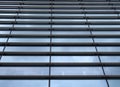 Vertical perspective view of the facade of a modern glass commercial building with steel frames and sky reflected in the windows Royalty Free Stock Photo