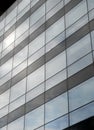 Vertical perspective view of the facade of a modern glass commercial building with steel frames and sky reflected in the windows Royalty Free Stock Photo