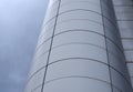 Vertical perspective view of the facade of a modern glass commercial building with steel frames and sky reflected in the windows Royalty Free Stock Photo