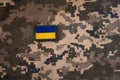 Vertical photo of banner of ukrainian flag on camouflage textile