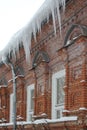 A vertical photo of big Icicles on facade of old red brick building Royalty Free Stock Photo