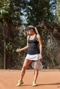 Vertical photo of blonde lady tennis player with ball in hand on court outdoor.