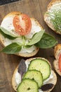 vertical photo with closeup various vegetable sandwiches with cream cheese, tomatoes, dill, cucumbers, leeks and basil
