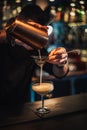 vertical photo of a cocktail being prepared at a cocktail bar by a bartender