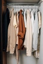 Vertical photo of colorful shirts, t-shirts and dresses on hangers in closet. The concept of changing the wardrobe, storing things Royalty Free Stock Photo