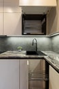 Vertical photo of Corner with sink in the interior Kitchen with designer white cabinets, some of these cabinets are open and Royalty Free Stock Photo