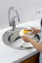 Woman using sponge with foam, washing plate in sink at white kitchen Royalty Free Stock Photo