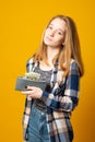 Vertical photo of cute young girl with gray wallet full of money dollars on a yellow background Royalty Free Stock Photo