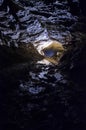 Vertical photo of dark cave with bright light