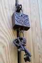 Vertical Photo of Dark Color Vintage Decorative Metal Keys and Lock on the Light Color Wooden Door Royalty Free Stock Photo