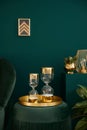Vertical photo of elegant living room with green velvet pouf, gold decor, design hourglass, picture frame on the wall.