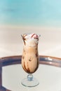 Vertical photo of freshly made creamy coffee tropical cocktail on the glass table at the beach with ocean Royalty Free Stock Photo