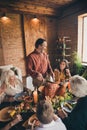 Vertical photo of full family gathering sit bristled father cut stuffed turkey communicate wife suggest better knife