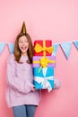 Vertical photo of funny excited girl knitwear sweater headwear looking presents pile isolated pink color background